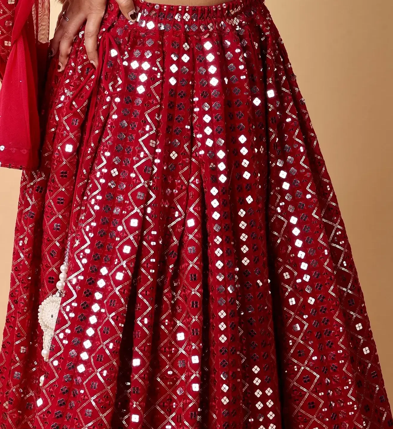 Close up of hand set mirrors on a red georgette lehenga