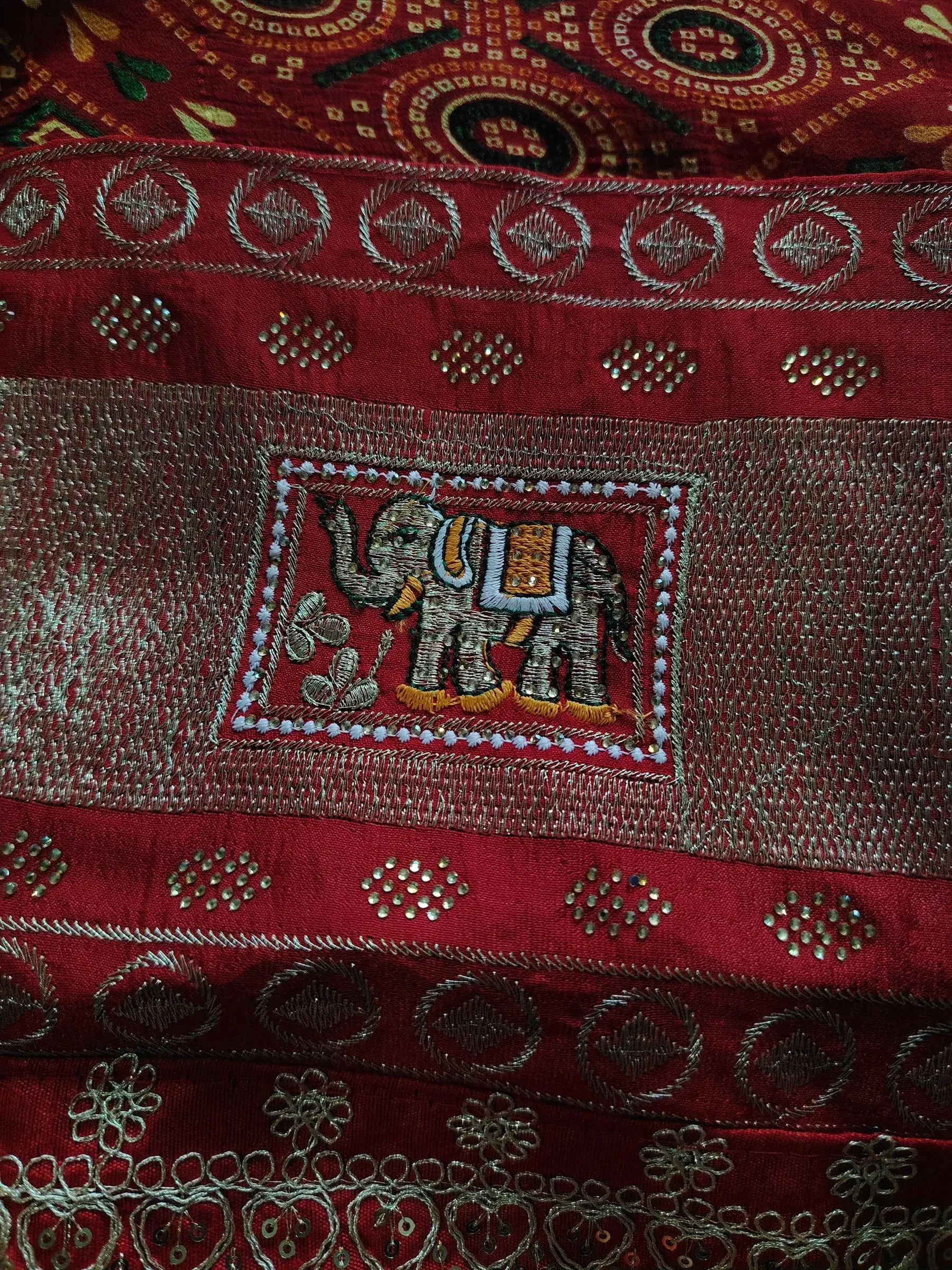 Close up of an embroidered elephant on red cloth