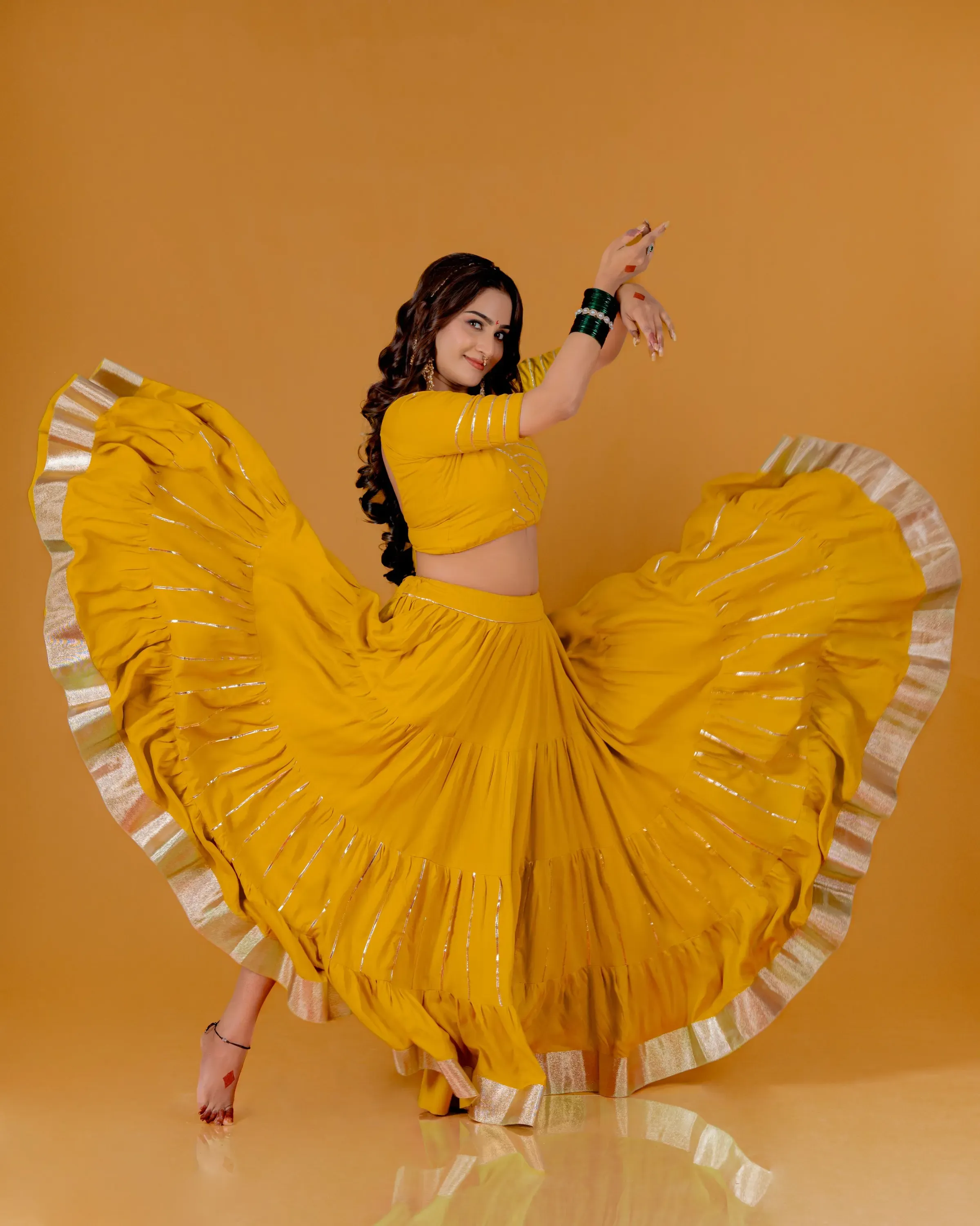 Model spinning in a haldi yellow tiered lehenga with gota stripes